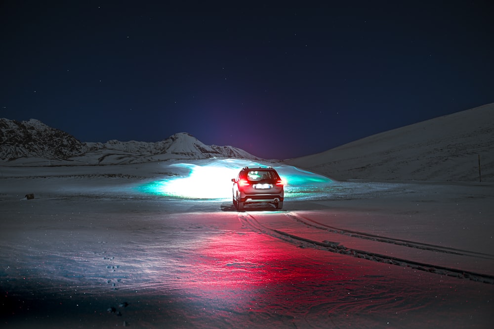 Un coche conduciendo por una carretera nevada por la noche