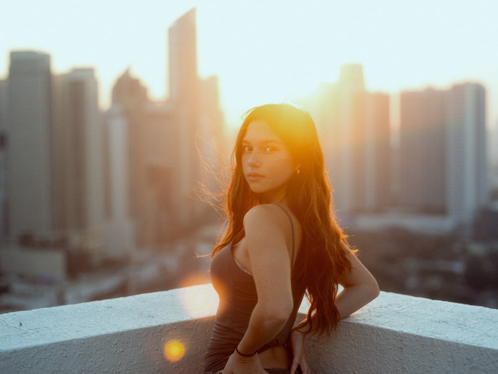 a woman standing on a ledge in front of a city