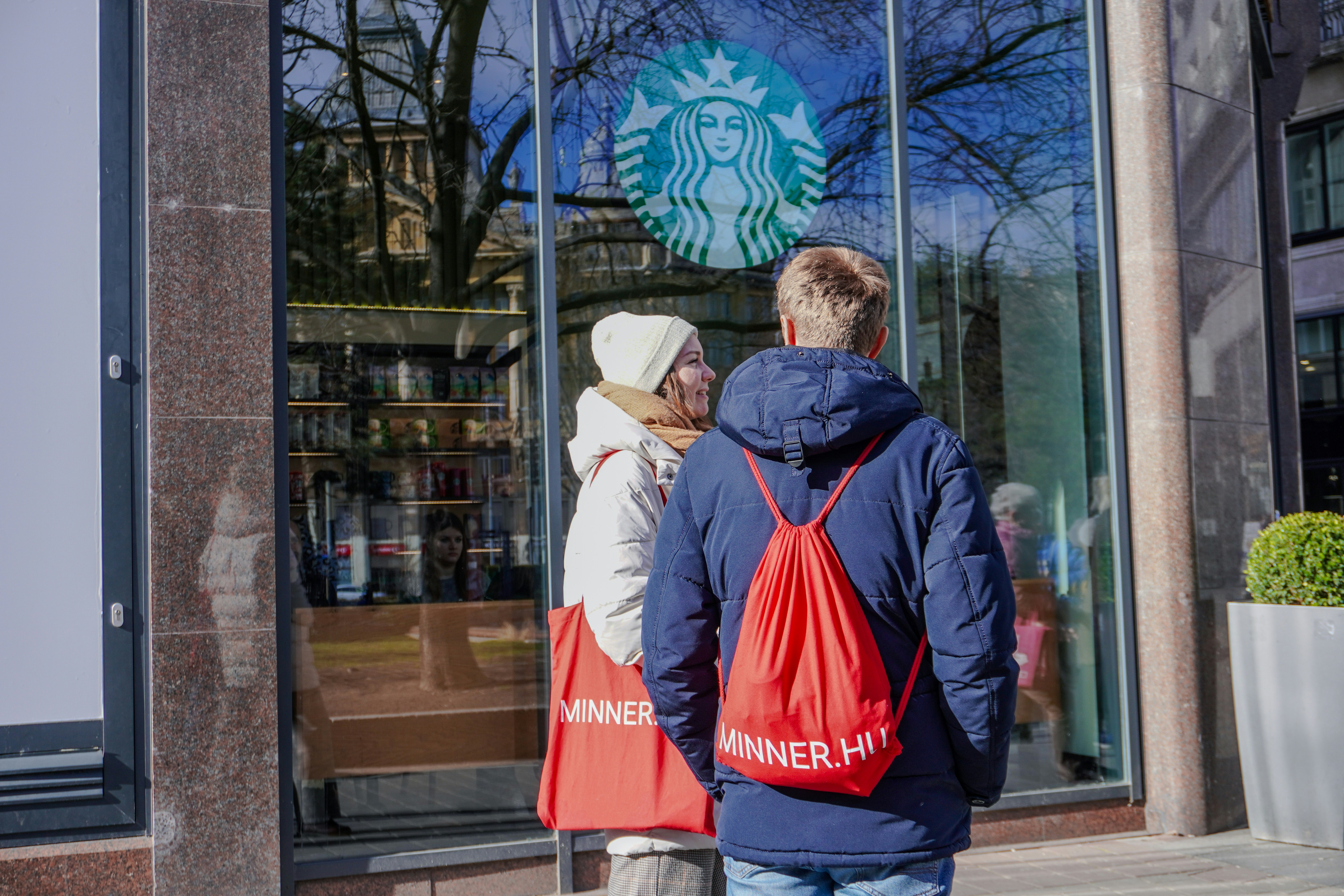 a man and a woman are standing outside of a starbucks