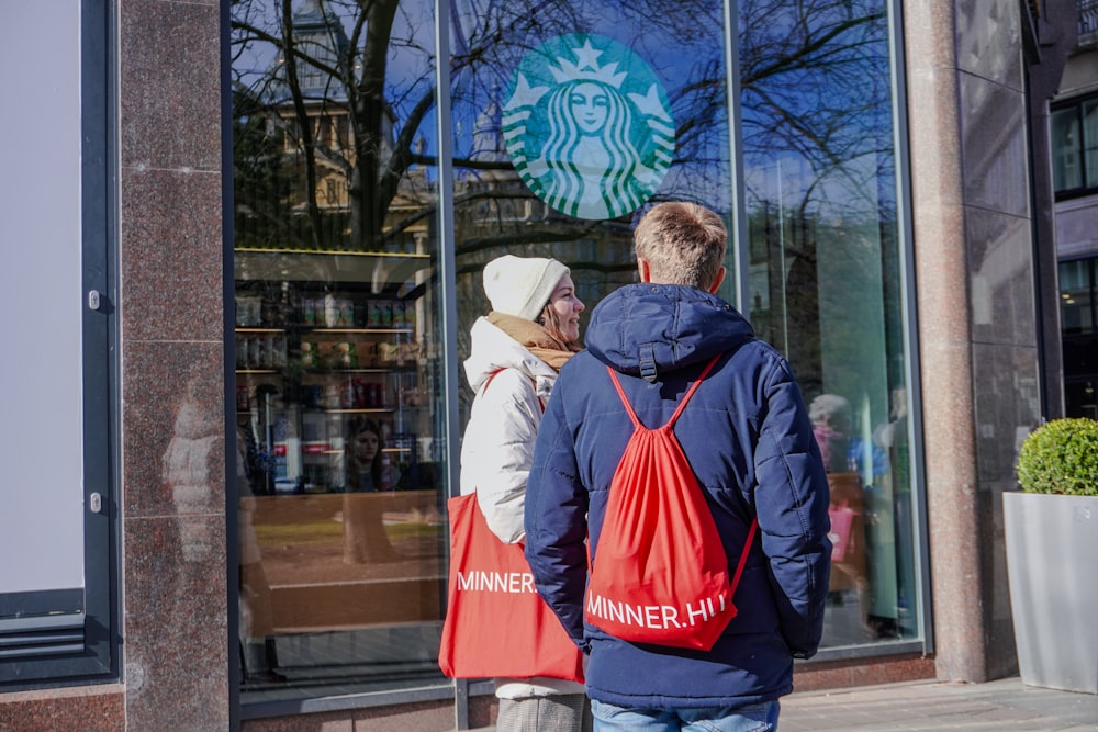 a man and a woman are standing outside of a starbucks