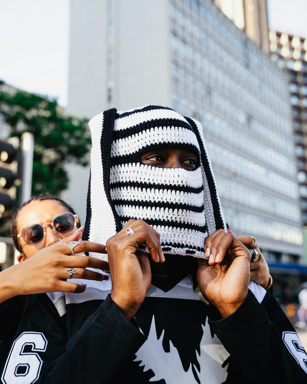 a man wearing a knitted mask while holding his hands up to his face