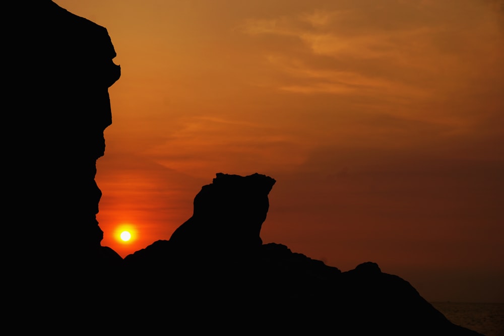 the sun is setting over a rocky outcropping