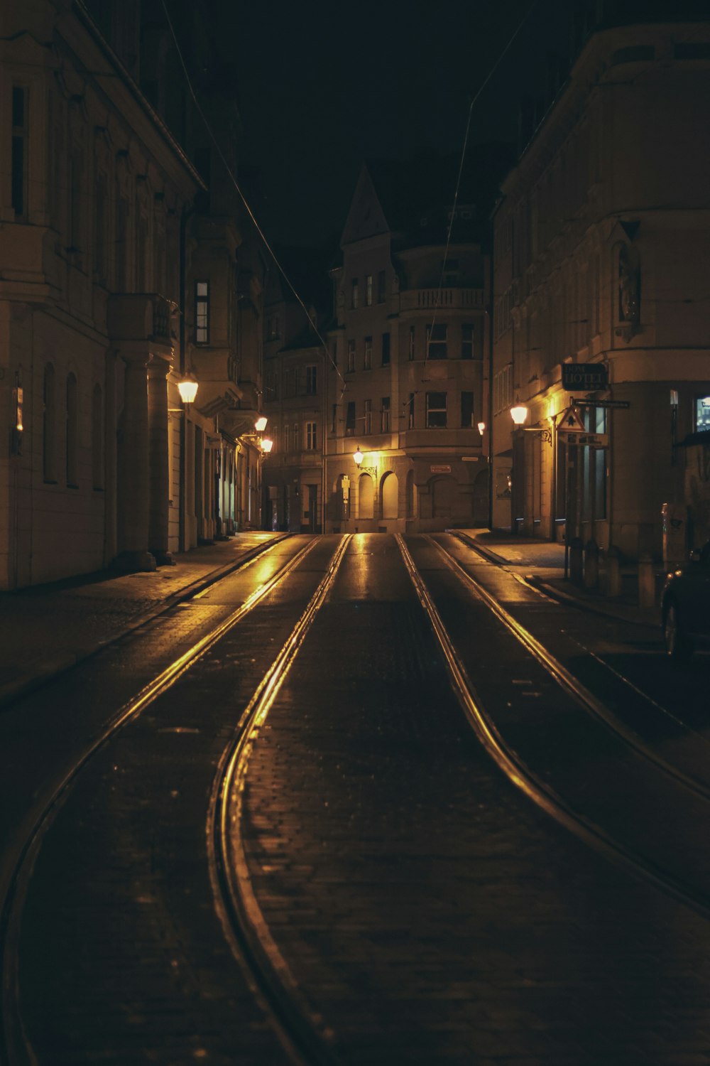 a city street at night with a train track in the foreground