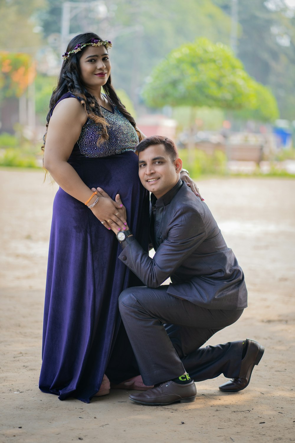 a man kneeling down next to a woman in a purple dress