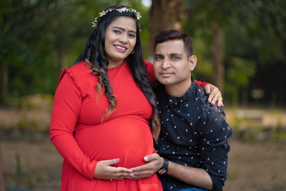 a pregnant couple posing for a picture in a park