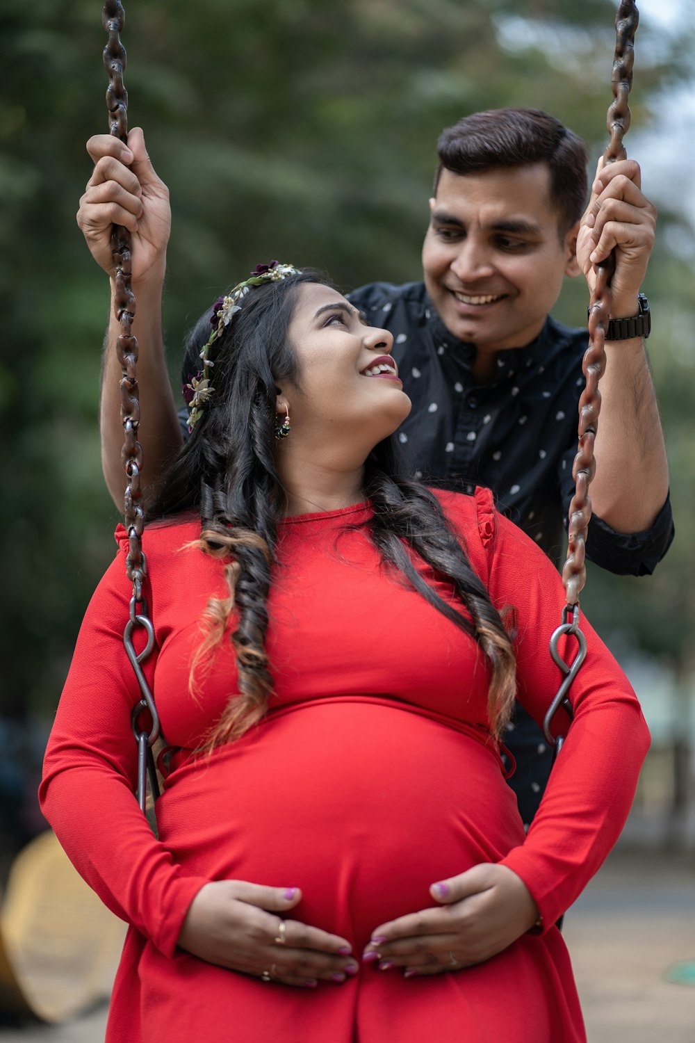 a pregnant woman in a red dress and a man in a black shirt