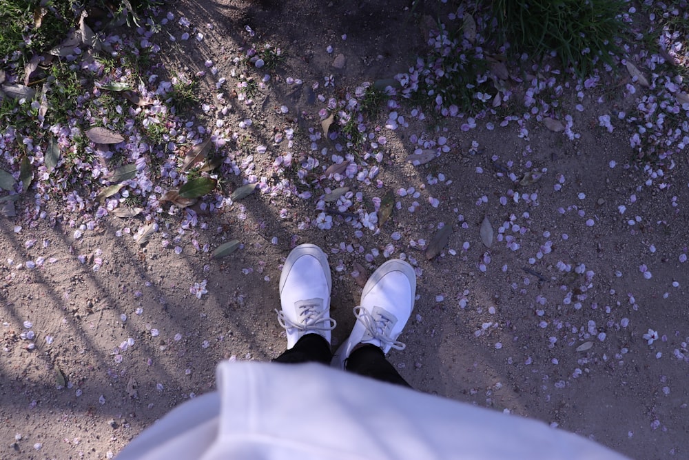 a person wearing white shoes standing on a dirt road