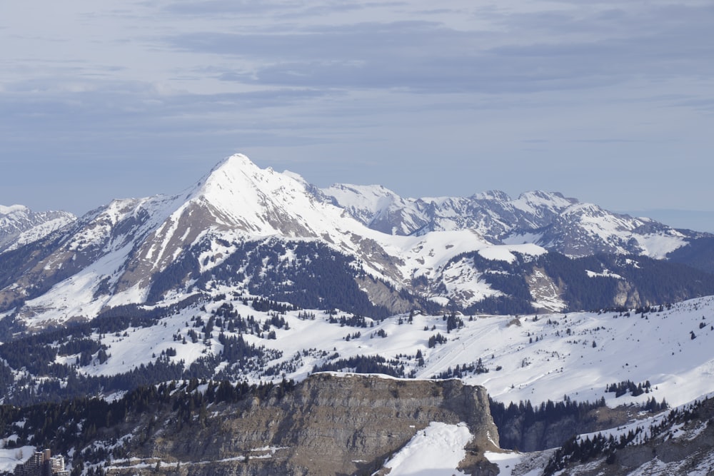 a mountain range covered in snow under a cloudy sky