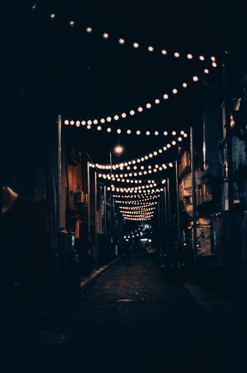 a dark alley with lights strung from the ceiling