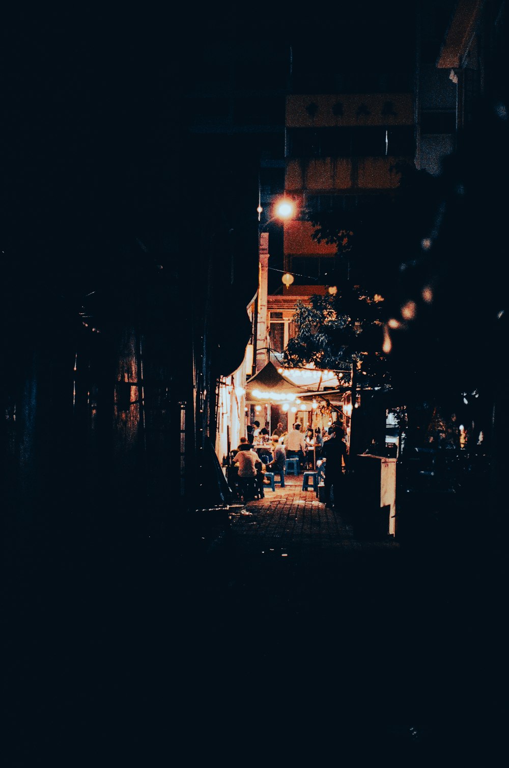 a dark alley with people walking down it at night