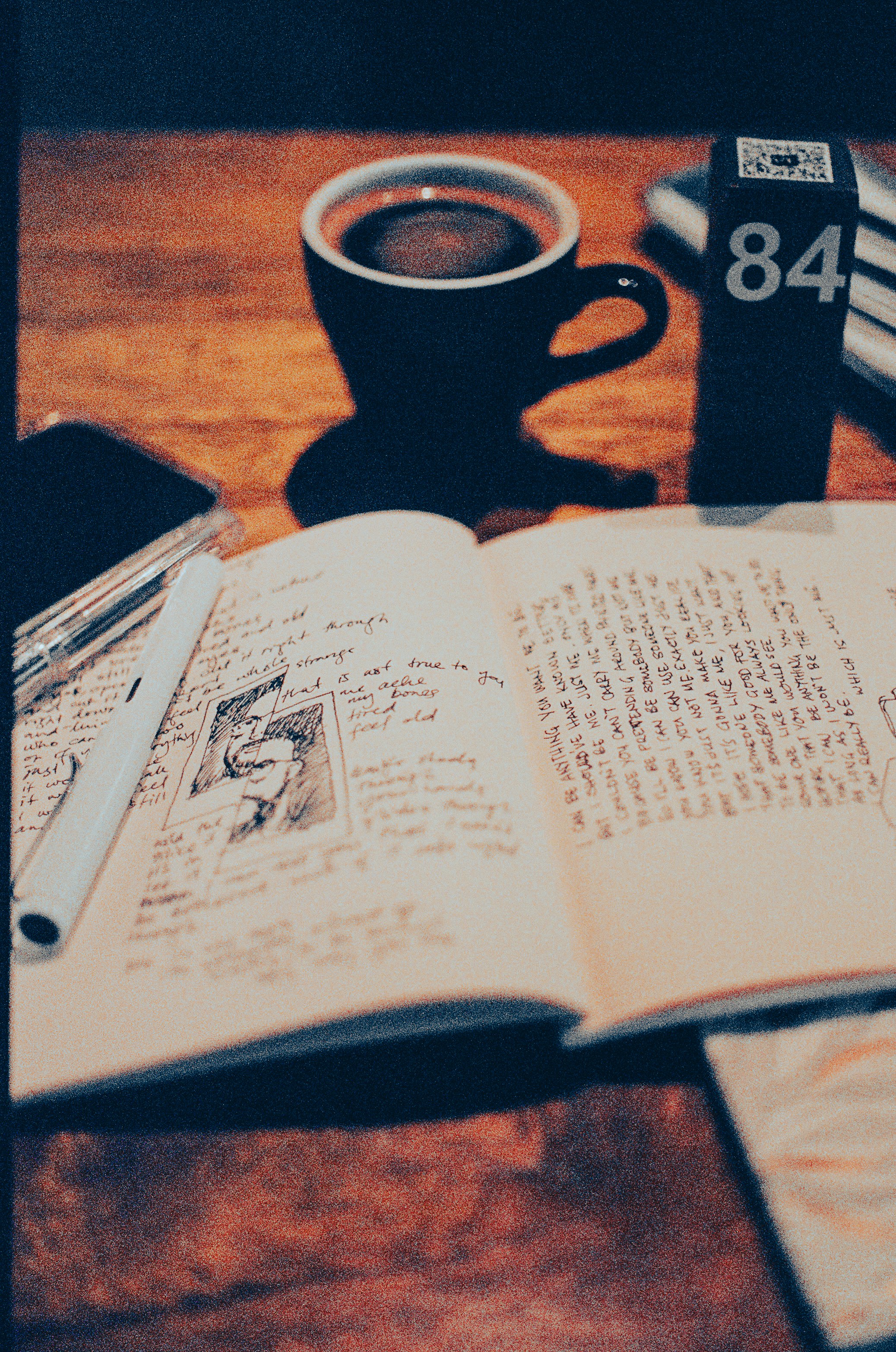 Open notebook with handwritten manuscript pages in soft daylight beside a coffee cup