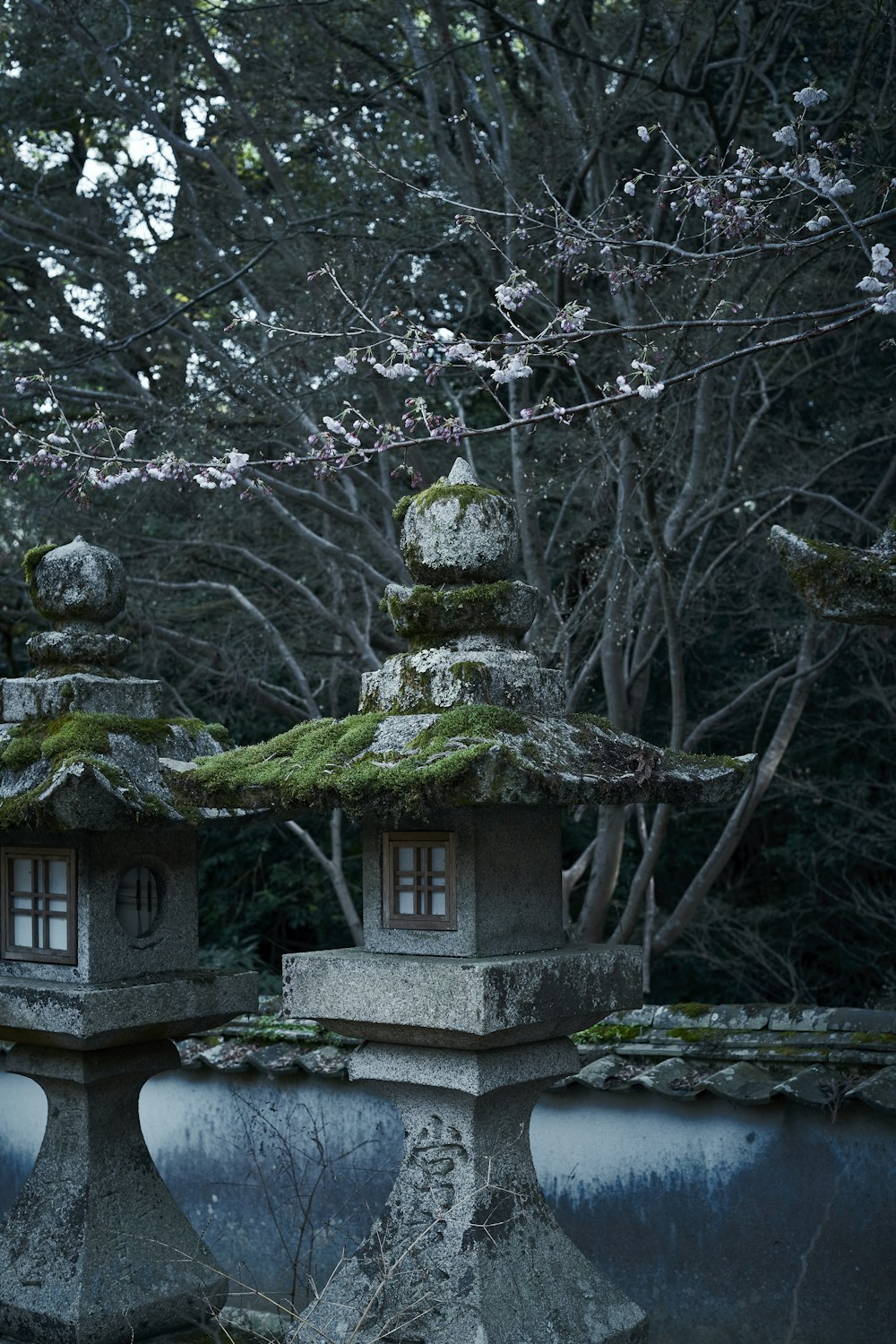 two stone lanterns with moss growing on them