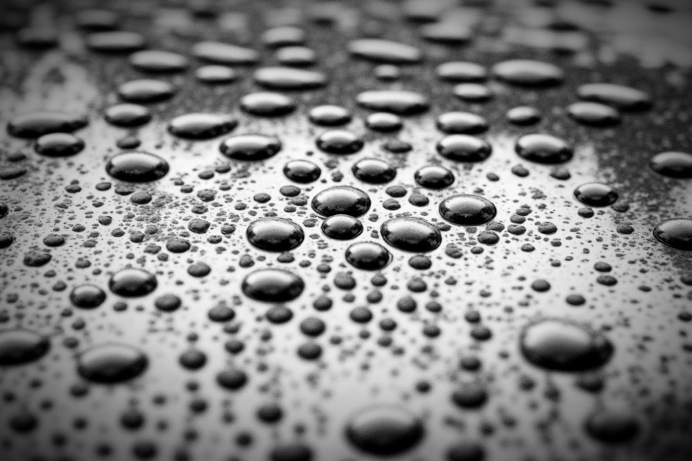 Foto en blanco y negro de gotas de agua sobre una superficie metálica