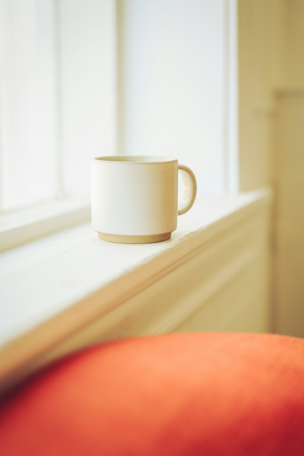 a white cup sitting on top of a window sill