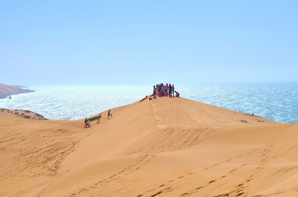 a group of people standing on top of a sand dune