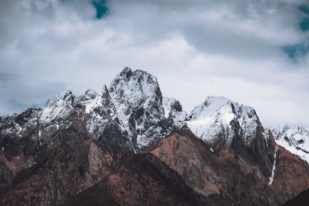 a mountain range covered in snow under a cloudy sky