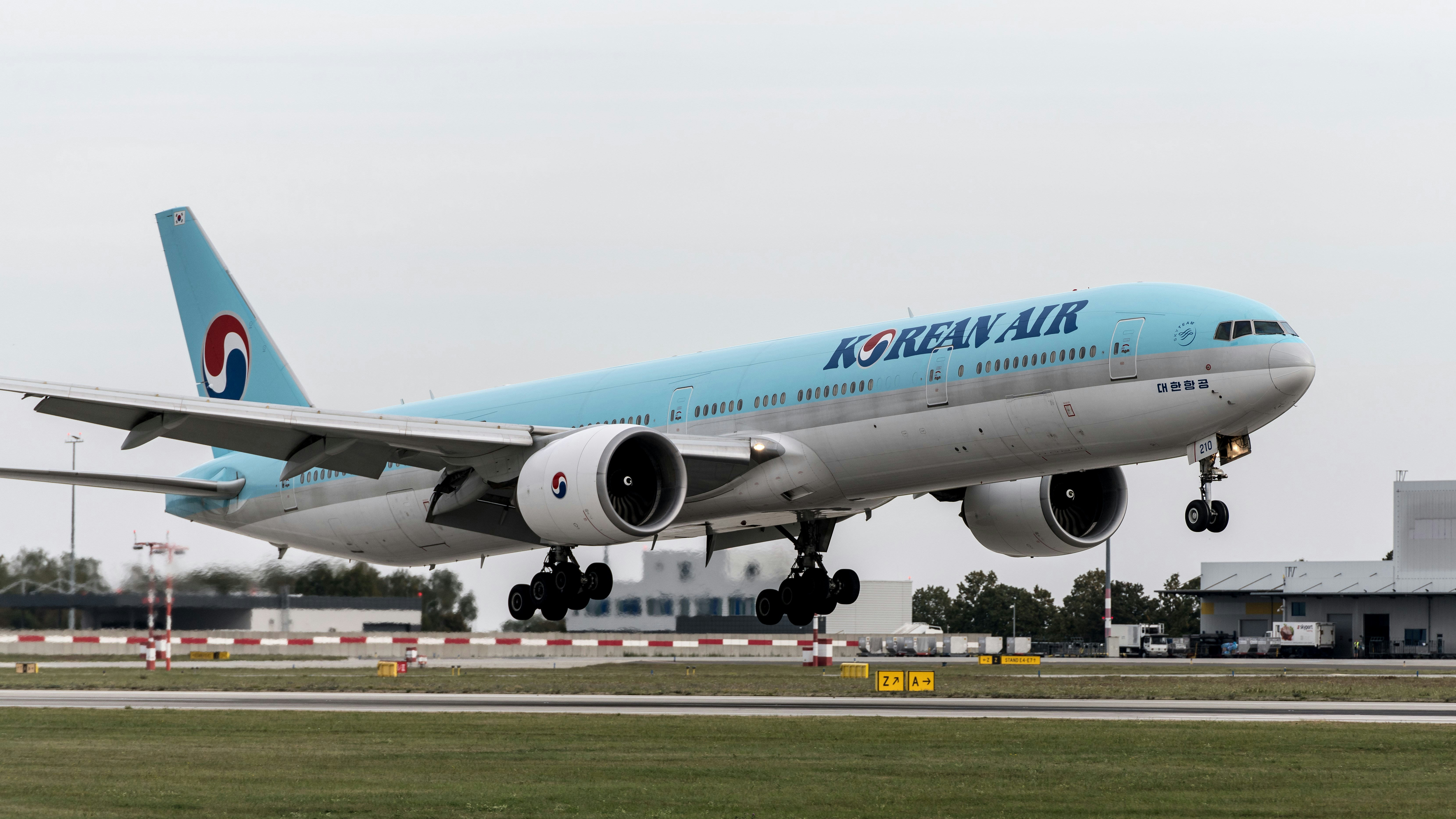 a korean air jet taking off from an airport runway, 