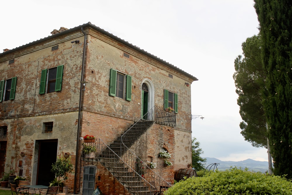 an old brick building with green shutters and a staircase