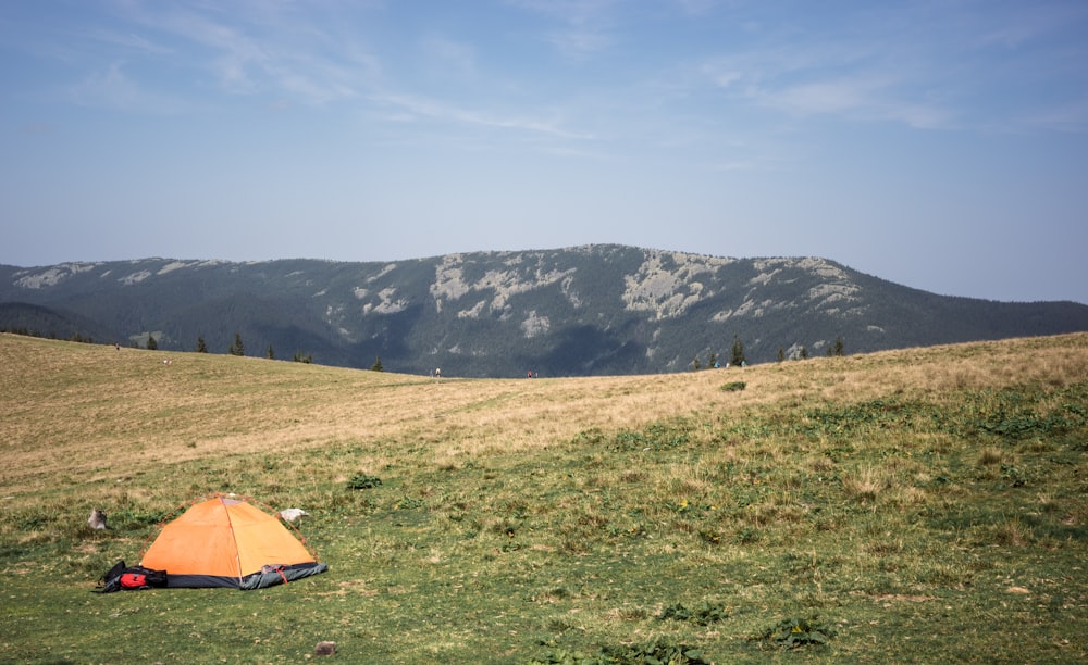 a tent pitched up in a field with mountains in the background