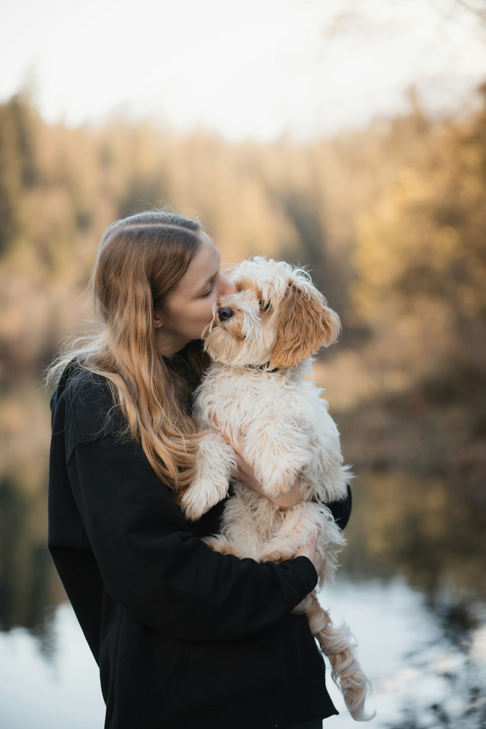 a woman holding a white dog in her arms