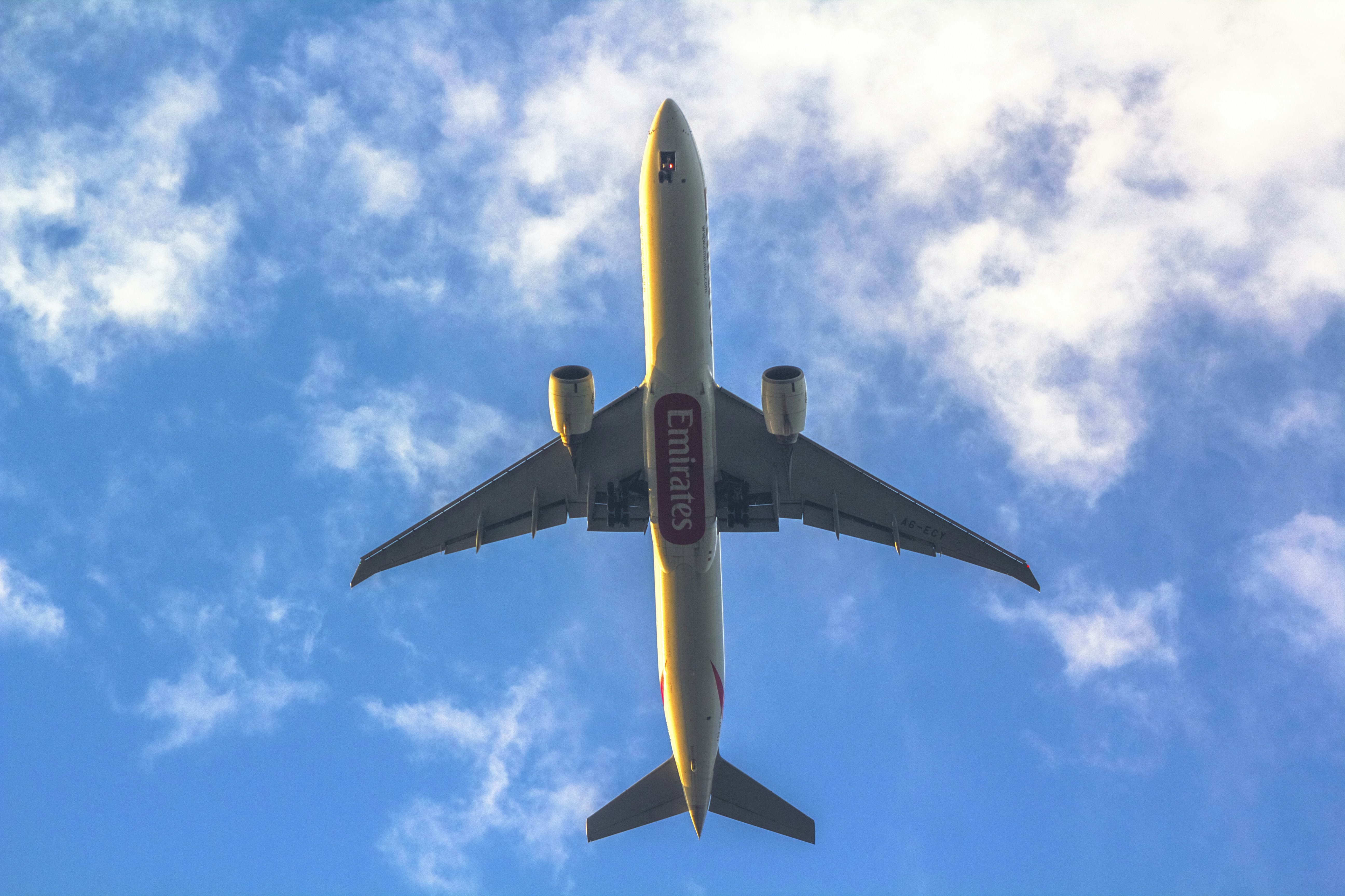 a large jetliner flying through a blue cloudy sky, Airplane flying in blue skies! Emirates Boeing 777