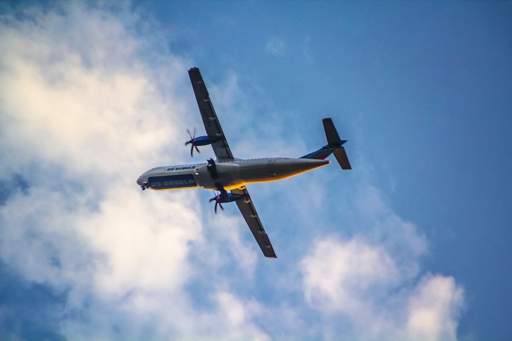 a small airplane flying through a cloudy blue sky