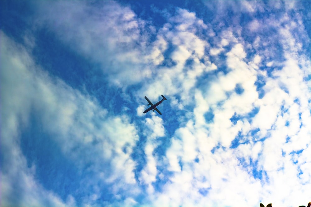 a plane flying through a cloudy blue sky