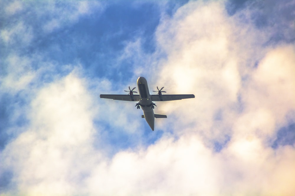 a plane flying through a cloudy blue sky