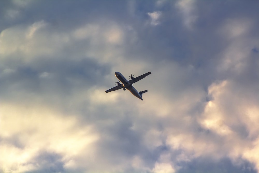 a plane flying through a cloudy blue sky