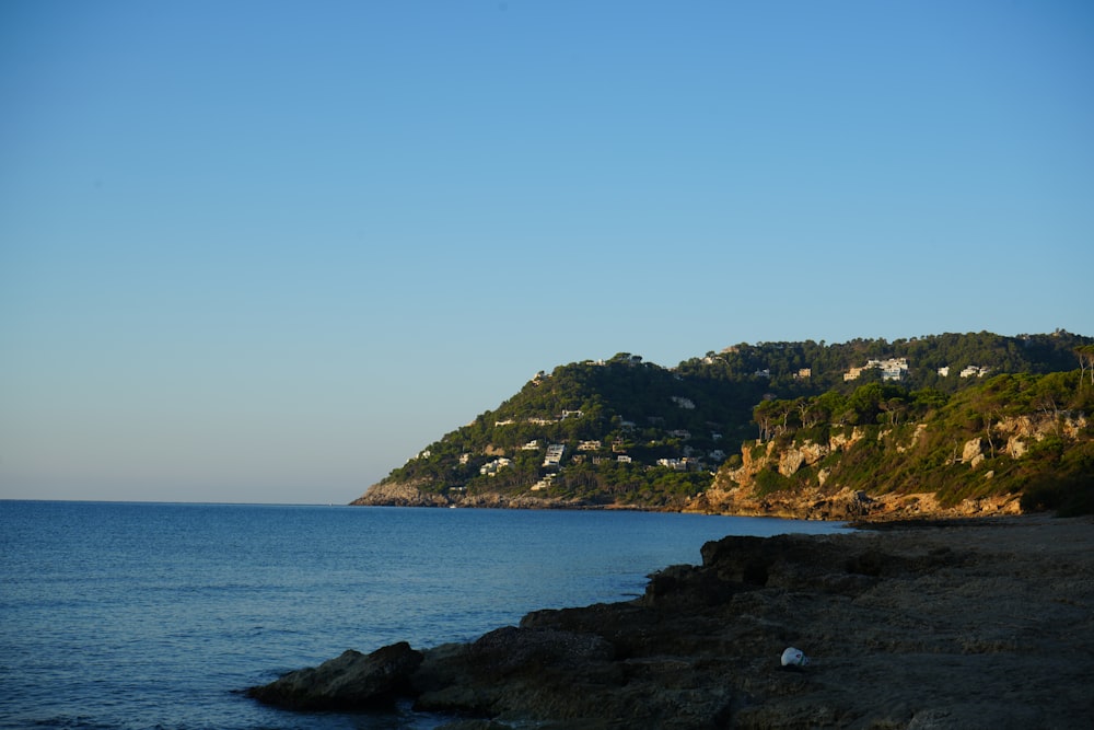 a body of water with a hill in the background