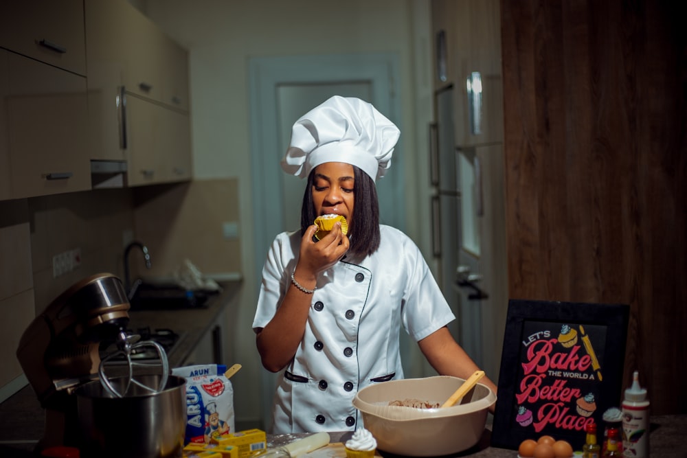 a woman in a chef's outfit is eating a doughnut