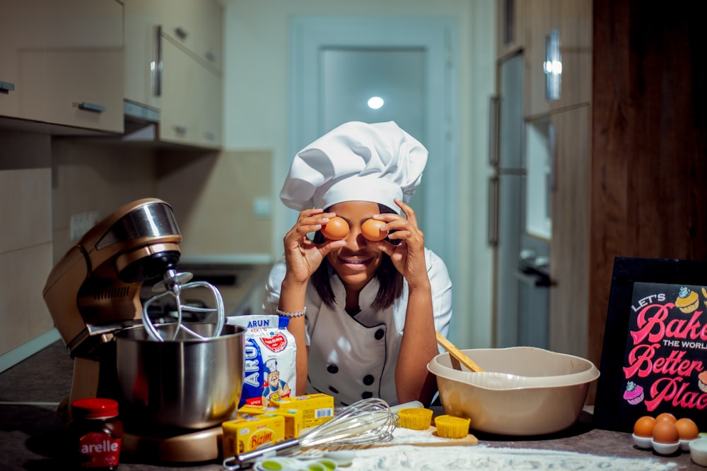 a woman in a chef's hat holding eggs in front of her face