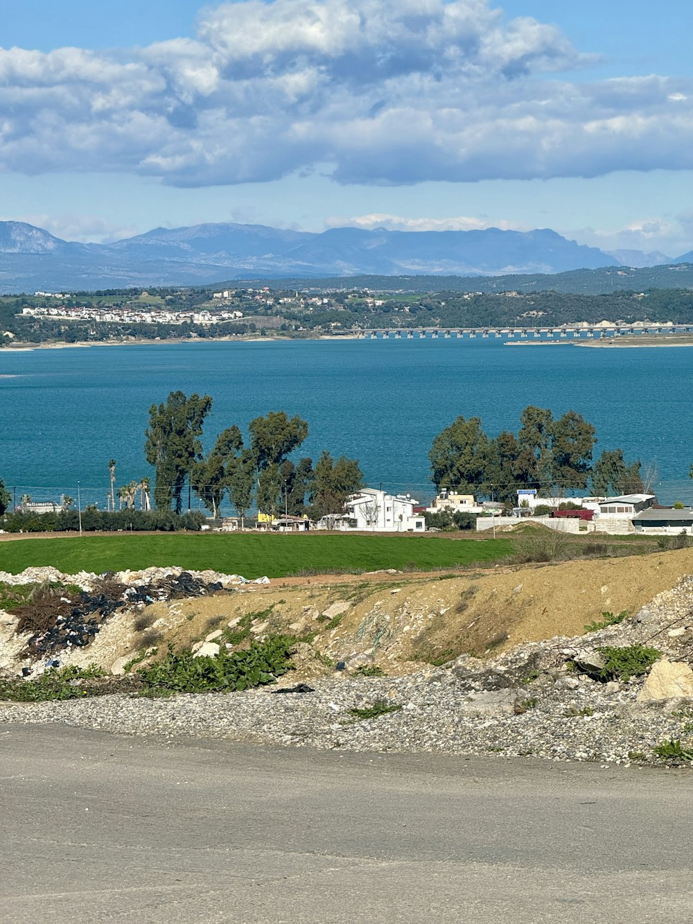 a large body of water sitting next to a lush green field