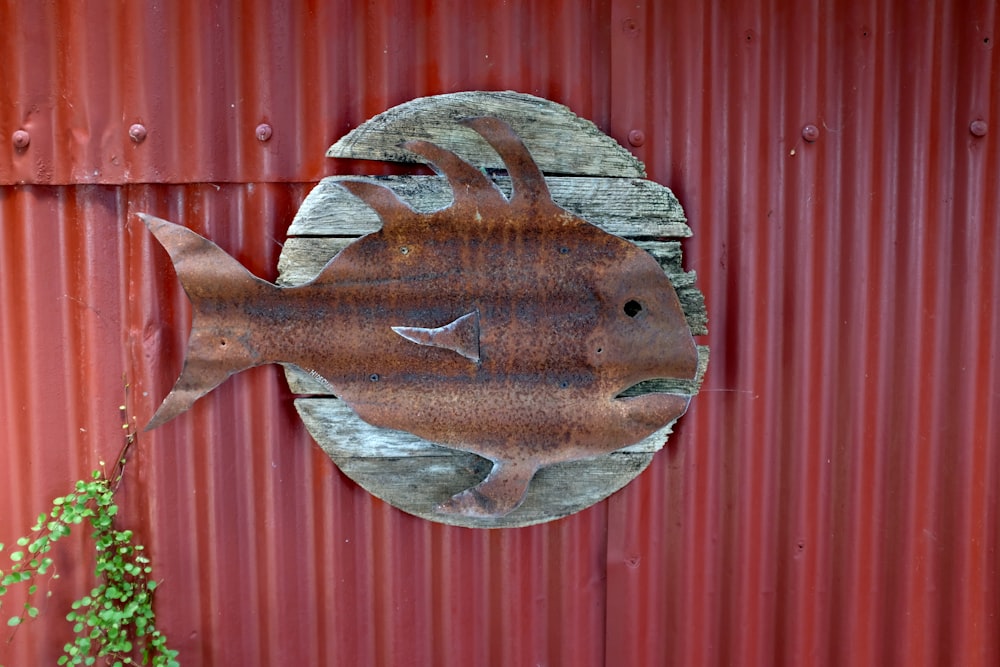 a rusty metal fish on a red metal wall