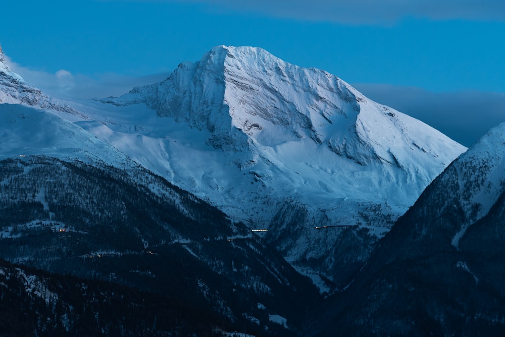 a snowy mountain range with a blue sky in the background