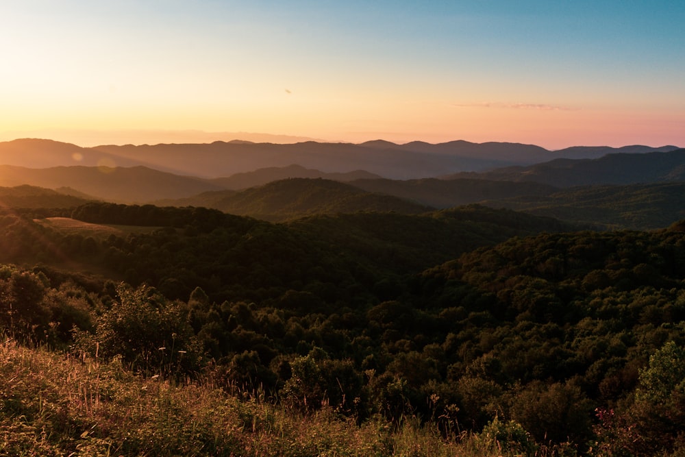 the sun is setting over the mountains in the distance