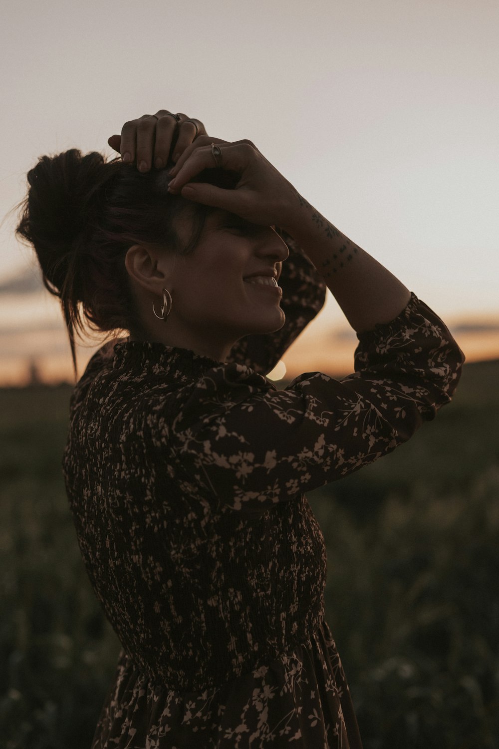 a woman standing in a field with her hair in a bun