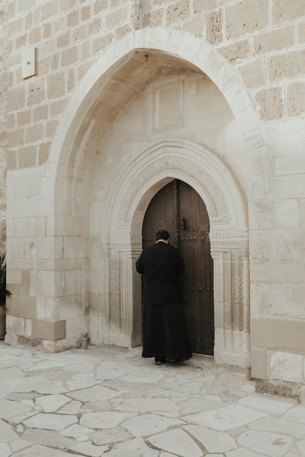 a man in a black robe is standing in front of a door