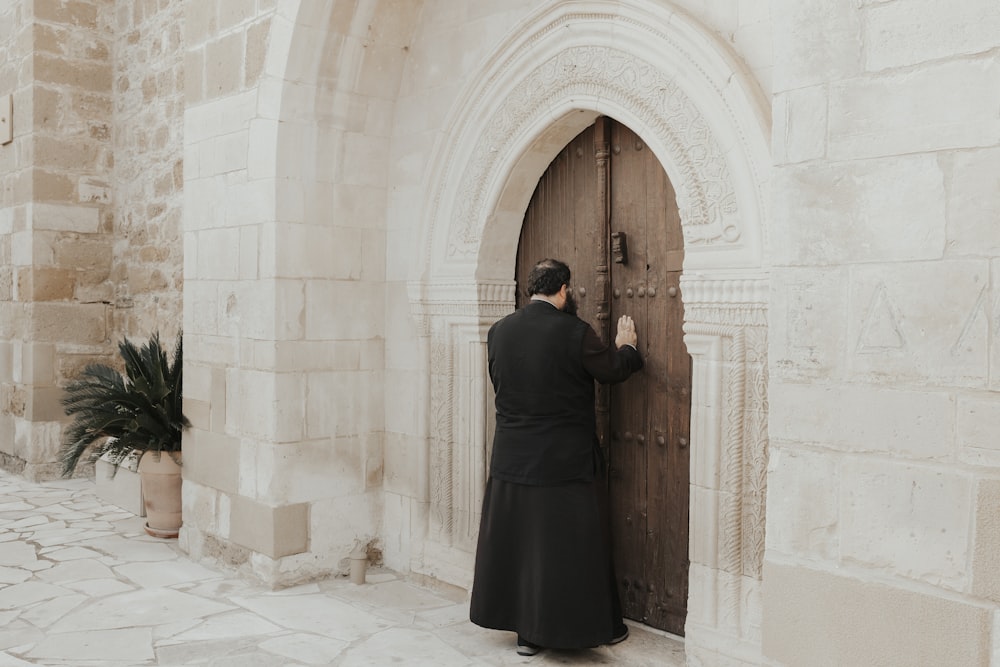 a man in a black robe standing in front of a door