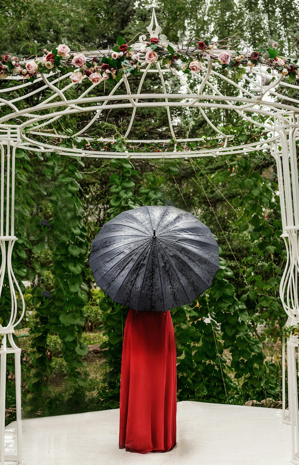 a woman in a red dress holding a black umbrella