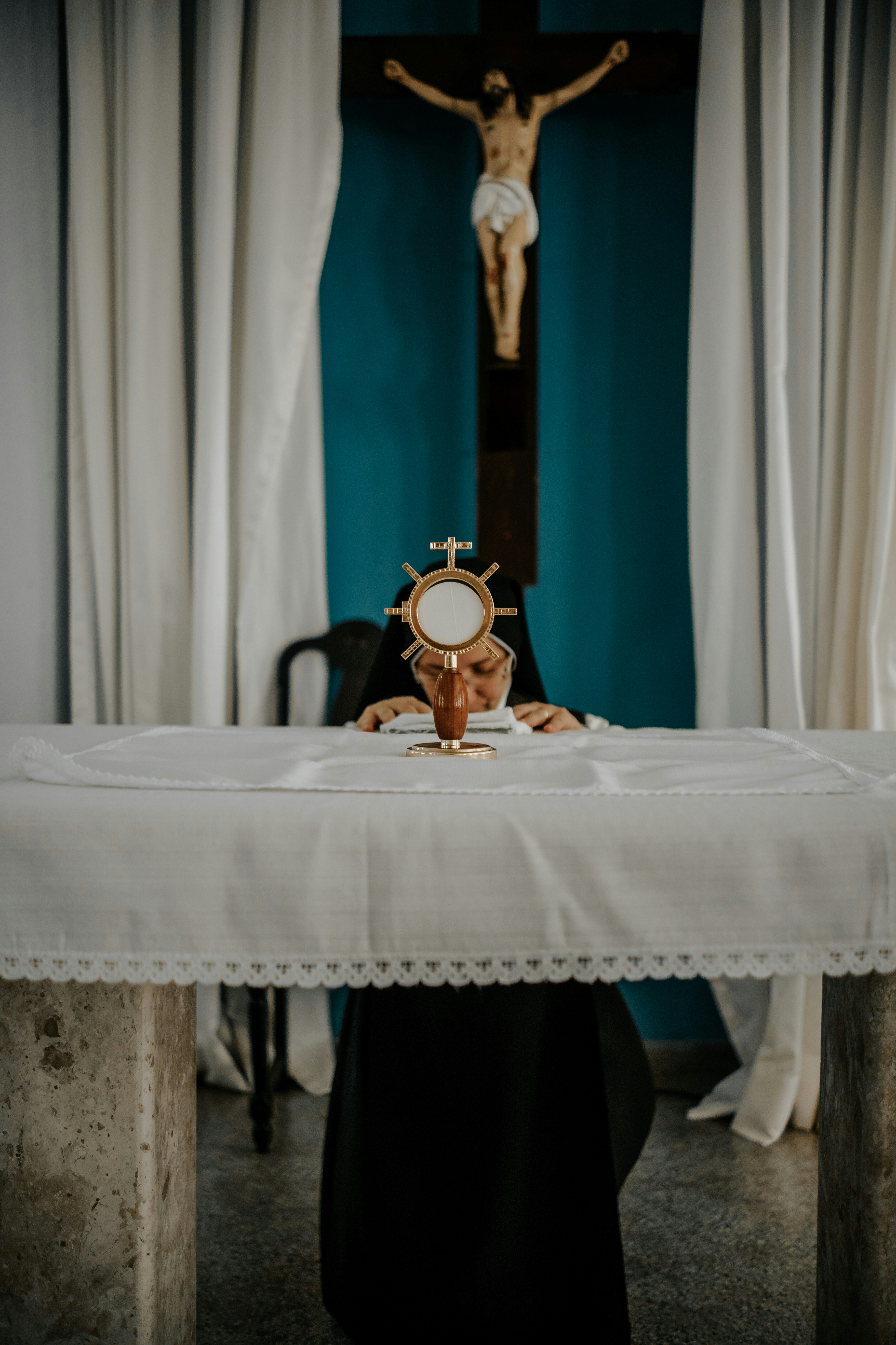 A person sitting at a table in front of a crucifix