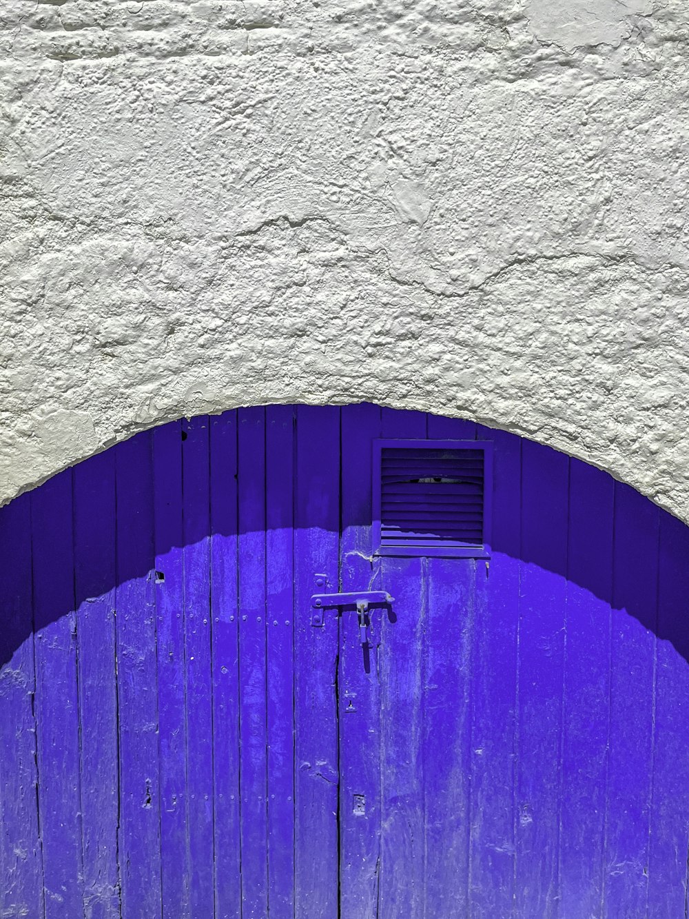 a cat sitting on a bench in front of a purple door