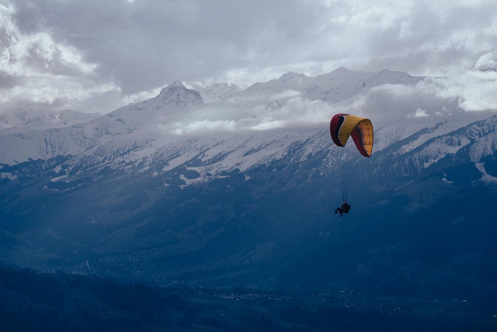 una persona che fa parapendio su una catena montuosa sotto un cielo nuvoloso