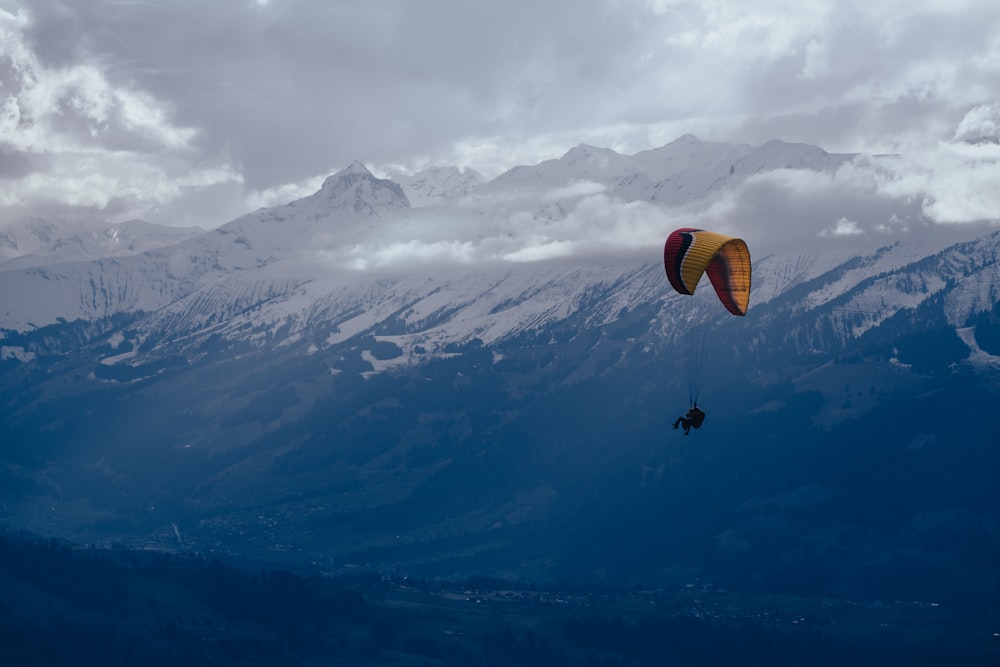 a person parasailing over a mountain range under a cloudy sky
