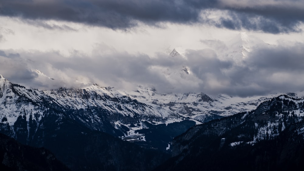 a snowy mountain range under a cloudy sky