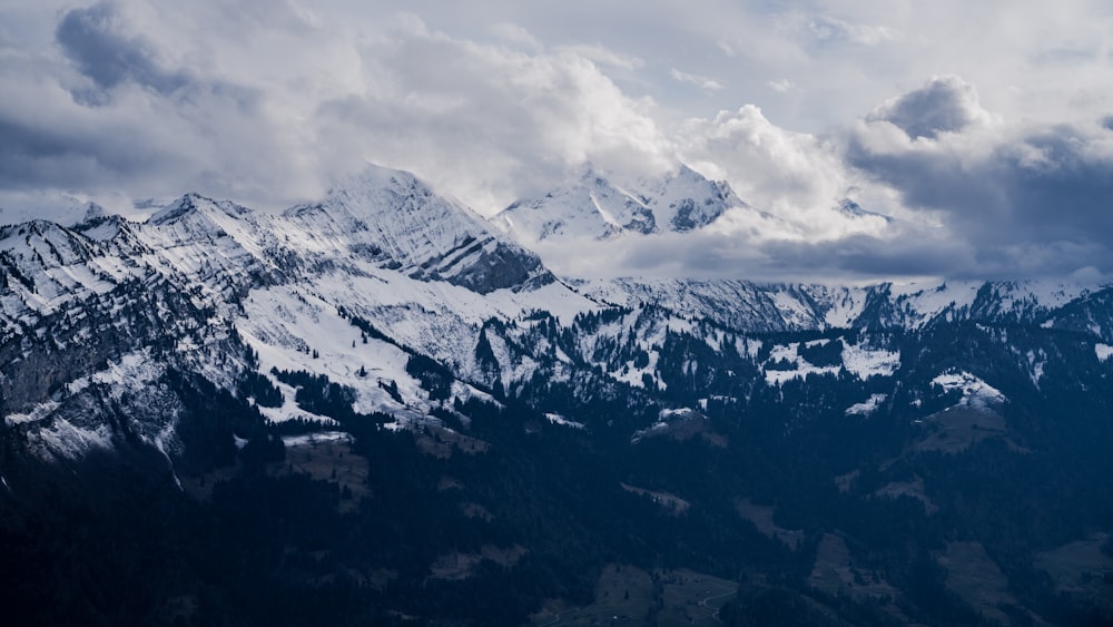 a snowy mountain range under a cloudy sky