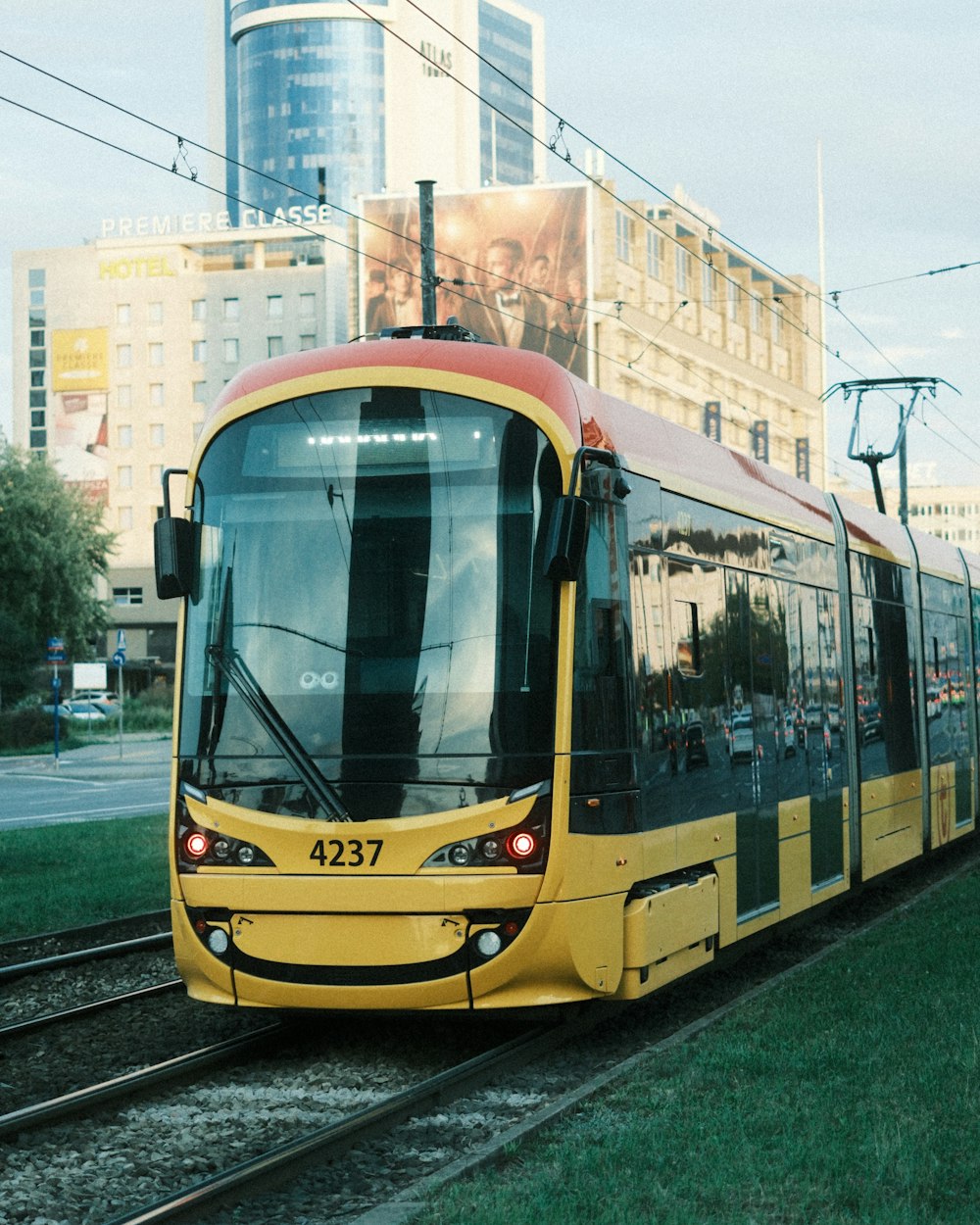 Un tren amarillo que viaja por las vías del tren junto a un edificio alto