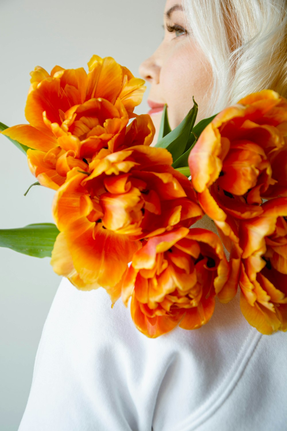 a woman holding a bouquet of orange flowers