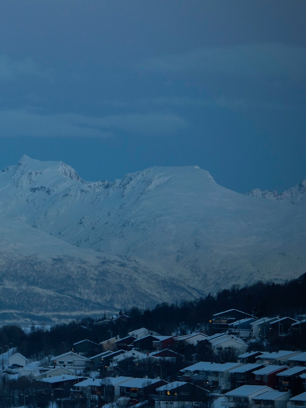 a snowy mountain range with houses in the foreground