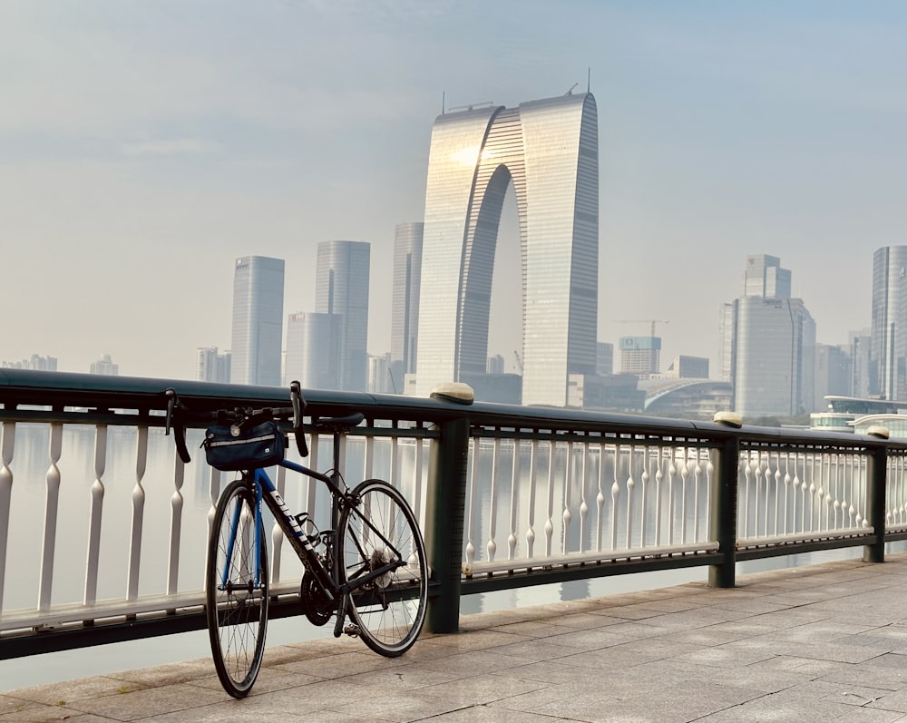 a bicycle leaning against a railing with a city in the background